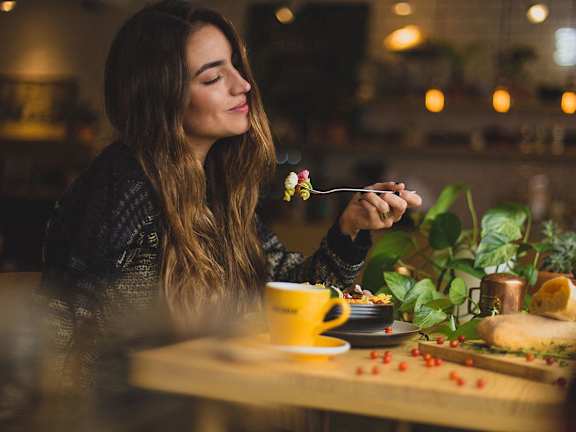 A woman is eating a flower on a fork.