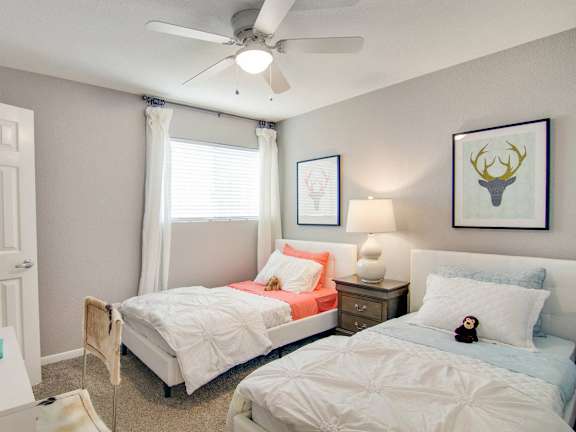 A bedroom with two beds, one with a white comforter and the other with a blue comforter.