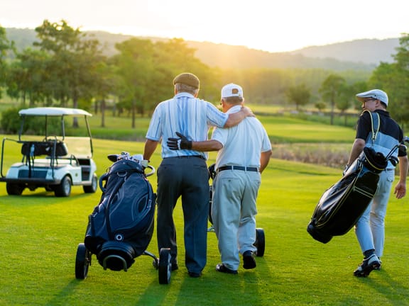 three men walking on a golf course