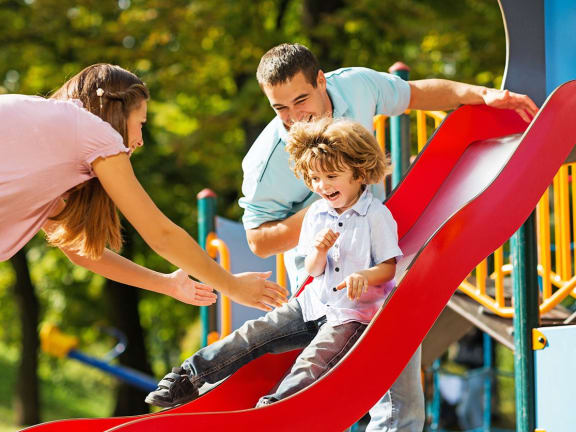 Parents playing with a child on a slide