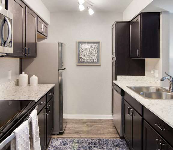 A kitchen with black cabinets and a fridge.