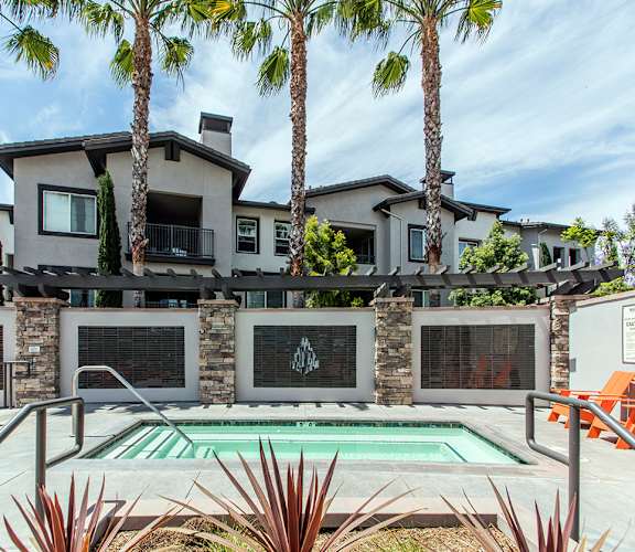 our apartments have a large pool and a patio with chairs at The Grove, Ontario, CA