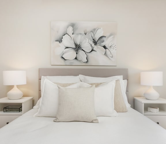 a bedroom with a large white bed with white pillows and white nightstands with white