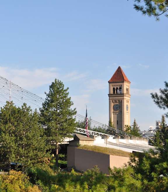 A bridge over a river with a clock tower in the background.