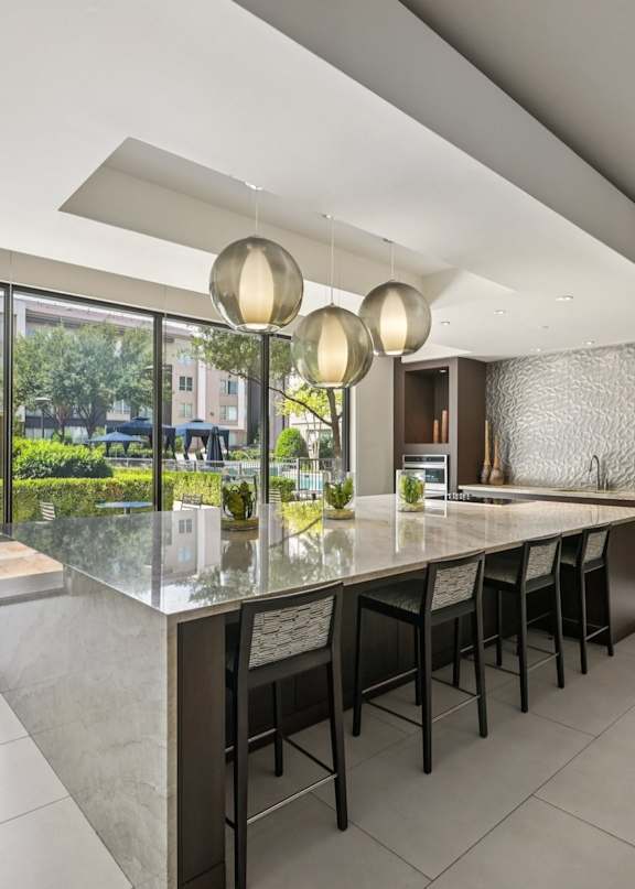A modern kitchen with a marble countertop and bar stools.
