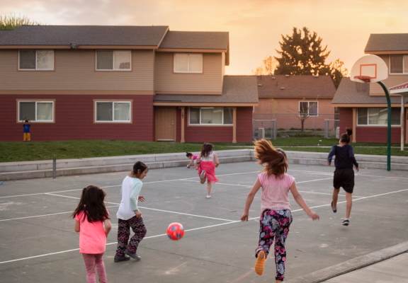 A group of children playing soccer in a parking lot.