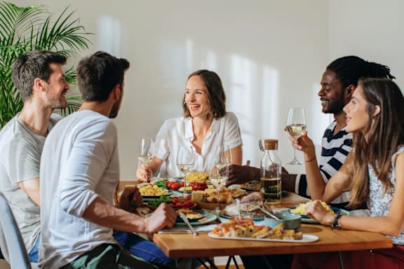 A group of people are sitting around a table enjoying a meal together.
