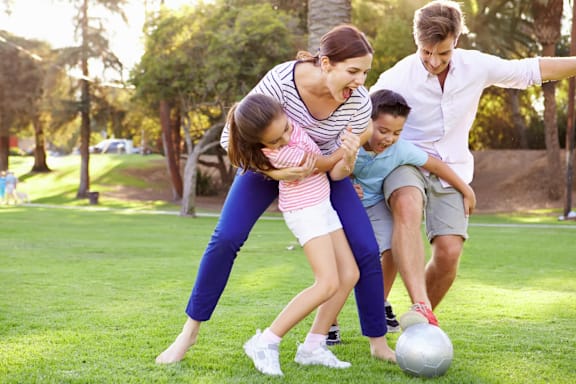 A family playing soccer in a park.