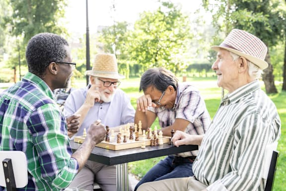 Four men playing chess in a park.