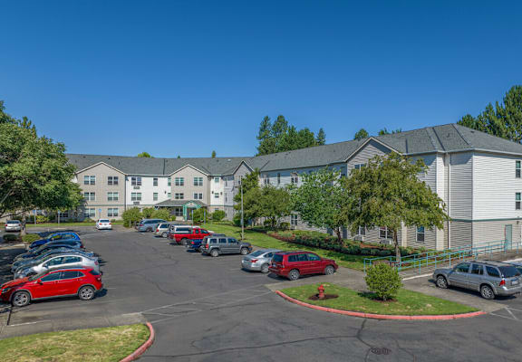A parking lot in front of a building with cars parked.