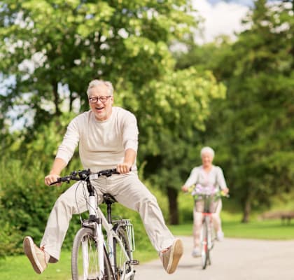 An elderly man is riding a bicycle in a park.