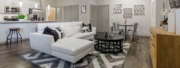 A modern living room with a white couch and a black and white rug.