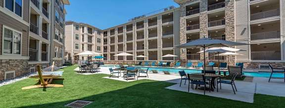 A large grassy area with a pool and chairs.