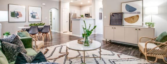 a living room with furniture and a kitchen in the background