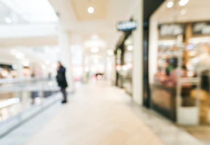 A blurry image of a person walking in a mall.