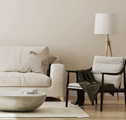 A white couch with a bowl on the floor in front of it.