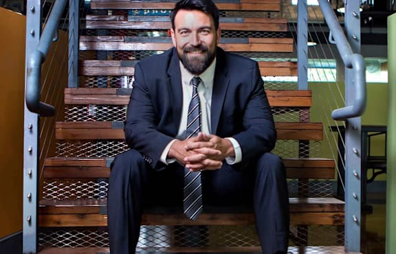 A man in a suit and tie sits on a staircase.