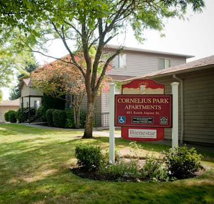 A sign for Cornelius Park Apartments stands in front of a building.