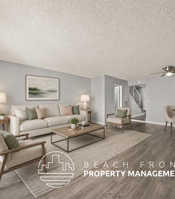 A living room with a staircase in the background and a logo for Beach Front Property Management.
