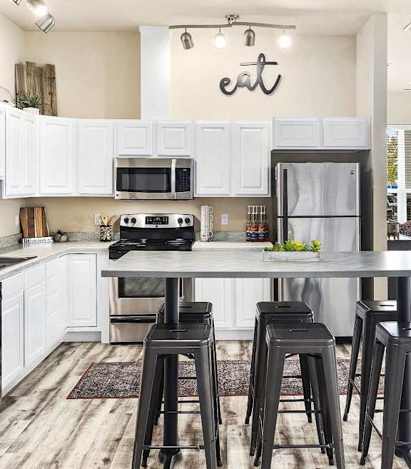 A kitchen with white cabinets and a black island.