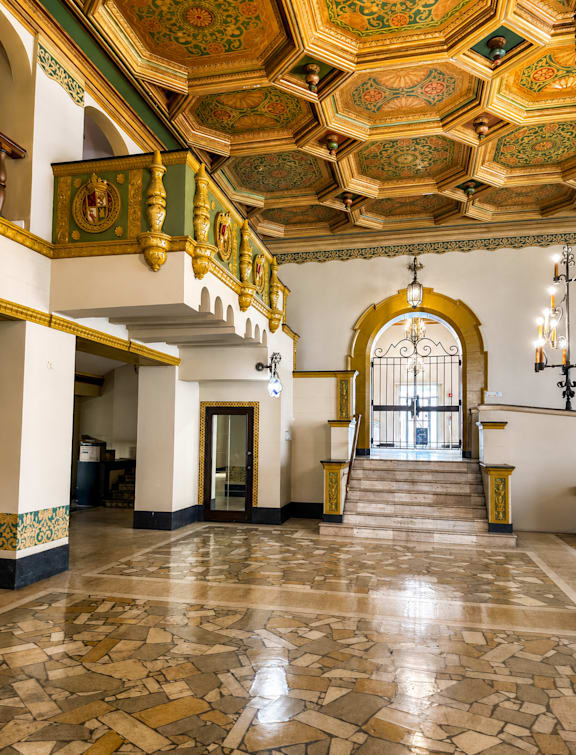 A grand staircase with a golden railing leads to a doorway.