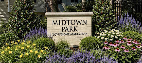 A sign that says Midtown Park in front of some flowers.