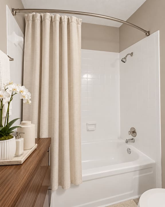 A white bathroom with a white tub and a white shower curtain.