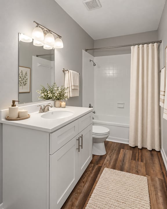 A white bathroom with a wooden floor and a white sink.