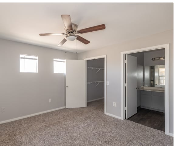 an empty bedroom with a ceiling fan and a closet