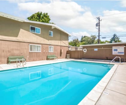 A swimming pool in a residential area with a house in the background.