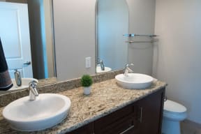 Apartments in Midtown Sacramento CA - The Penthouses at Capitol Park - Modern Bathroom With Two Sinks and Mirrors, Sleek Counters, & Handtowel Racks