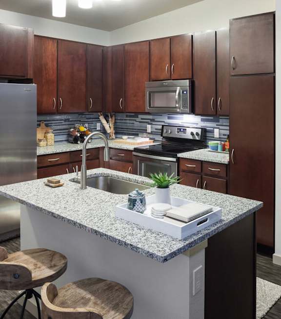 A kitchen with a granite countertop and wooden cabinets at Regatta Sloans Lake Apartments, Colorado, 80204