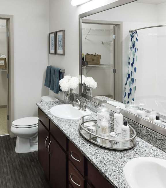 A bathroom with a toilet, sink, and mirror at Regatta Sloans Lake Apartments, Colorado, 80204