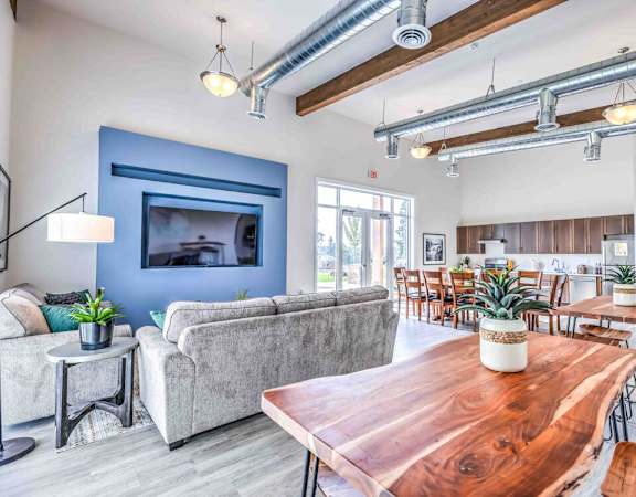A modern living room with a wooden table and grey couch.