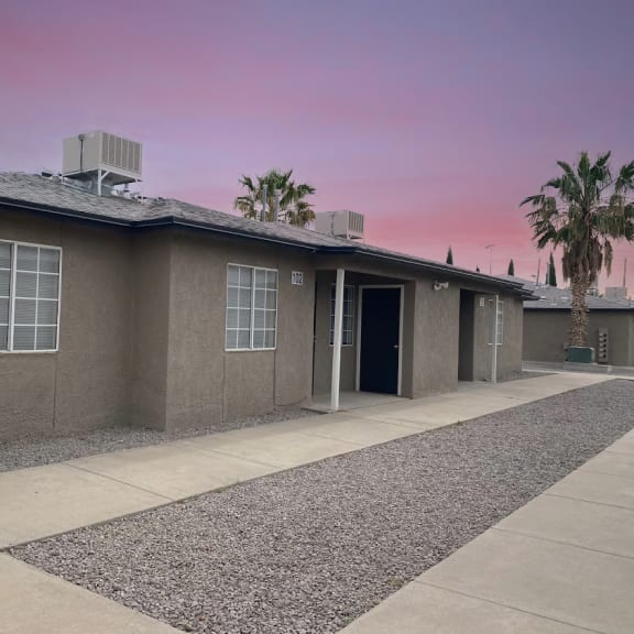 a house with a driveway and a pink sky above it