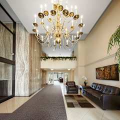 A large, elegant chandelier hangs over a long, dark carpeted hallway.