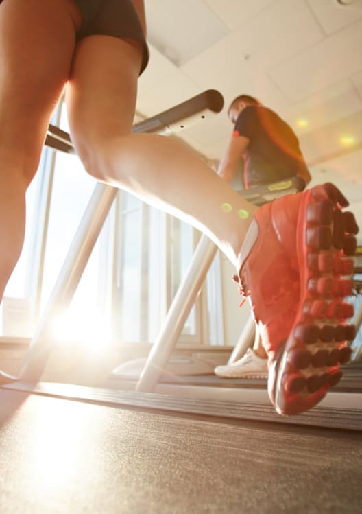 A person is running on a treadmill in a gym.