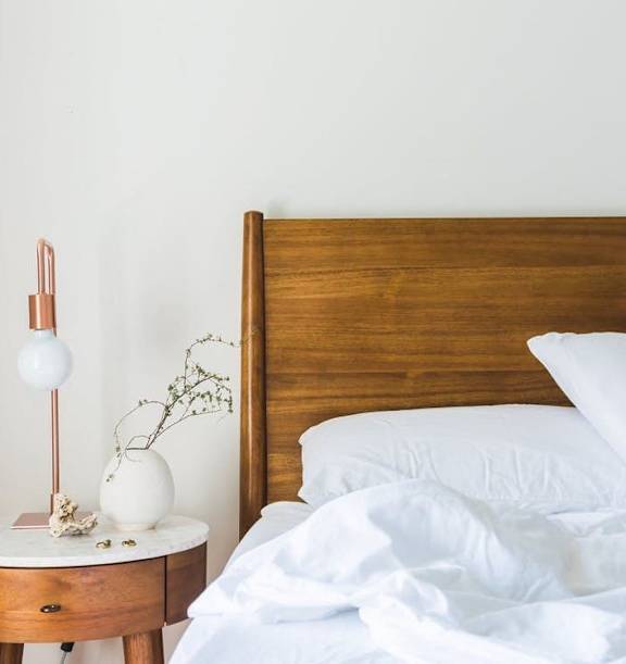 Model Bedroom with Wood Bed Frame and White Bedding Next to Wood Nightstand