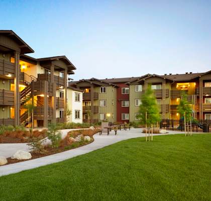 an exterior view of an apartment complex with a green lawn