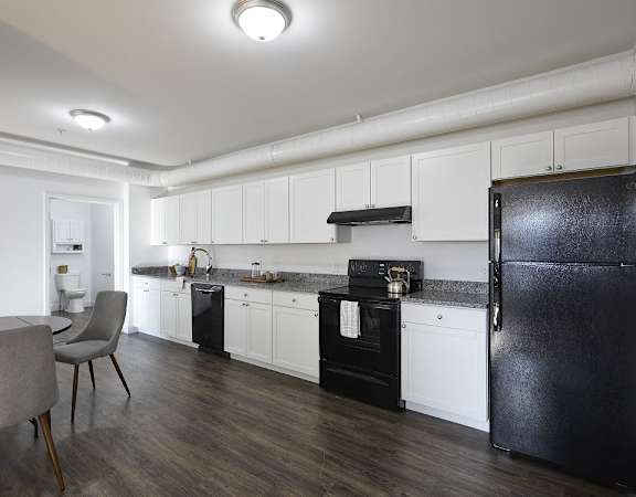 a kitchen and dining room with black appliances and white cabinets