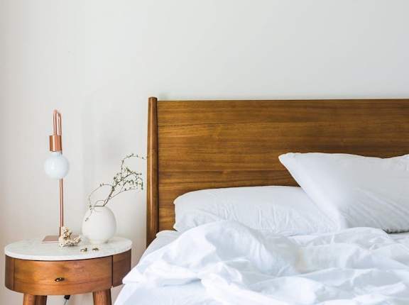 a bedroom with a bed and a nightstand with a lamp