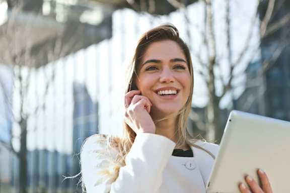 a woman talking on a cell phone while holding a laptop computer