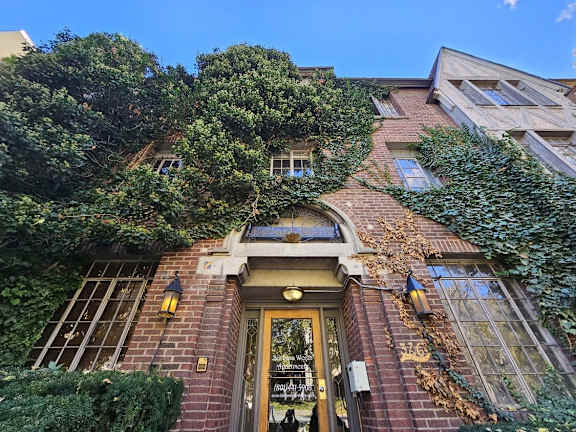 the front of a brick building with a door and ivy on it
