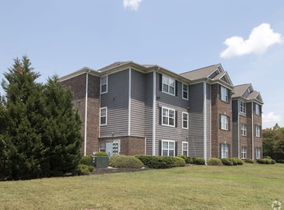 a large apartment building with a grass yard in front