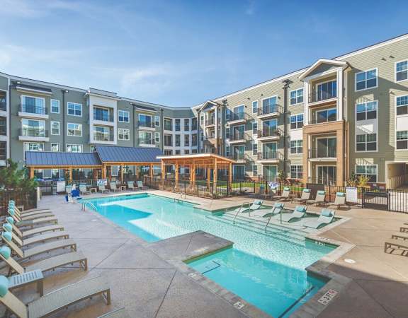 a swimming pool with chaise lounge chairs and a gazebo in front of an