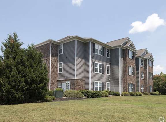 a large apartment building with a grass yard in front