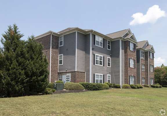 a large apartment building with a grass yard in front