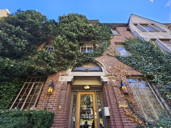 the front of a brick building with a door and ivy on it
