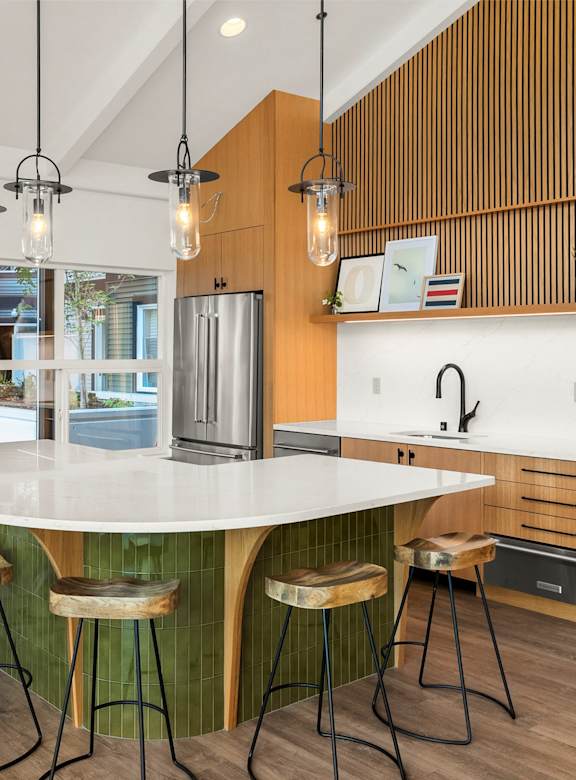 A kitchen with a white countertop and wooden stools.