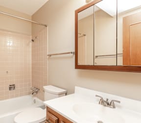 A white bathtub sits next to a white sink in a bathroom.